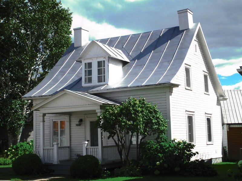 Exemple d'une maison traditionnelle québécoise, avec son toit distinctif et sa structure robuste. Maison traditionnelle québécoise